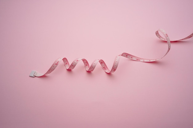 Photo high angle view of tape measure on pink background