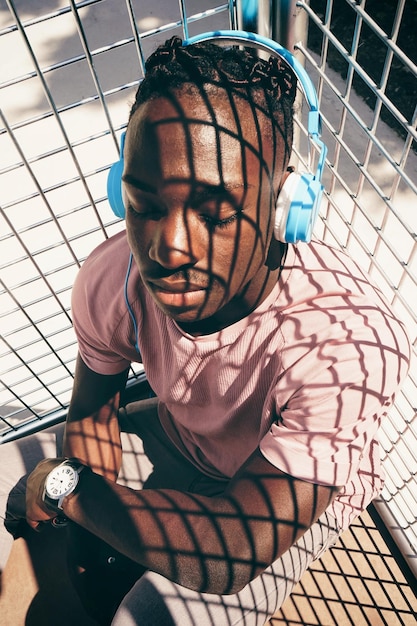 high angle view of teenage boy listening music while sitting by metal grate