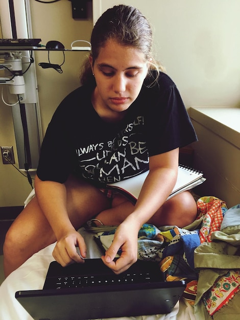 Photo high angle view of teenager looking at laptop while sitting at home