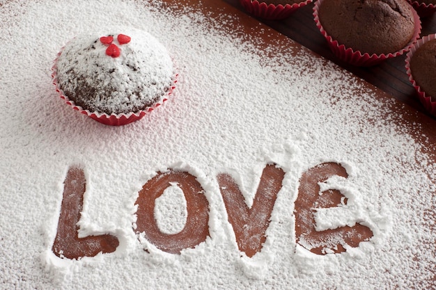 Photo high angle view of text in powdered sugar by muffin on cutting board