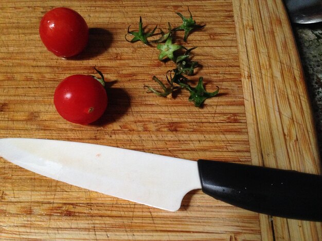 Photo high angle view of tomatoes and knife on cutting board