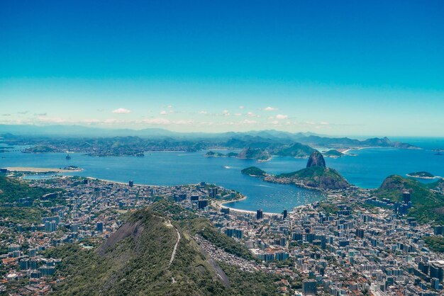 High angle view of townscape by sea against blue sky