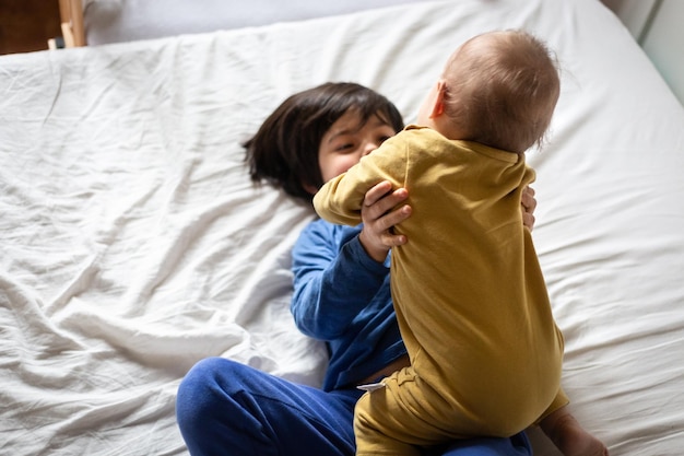 high angle view on two happy children hugging each other on the parents bed