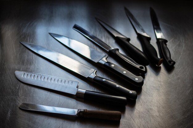 Высокоугольный вид различных ножей на металлическом столе
