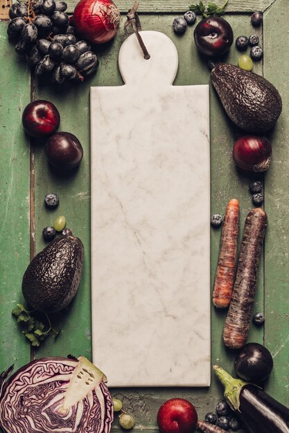 Foto vista ad alto angolo di verdure e frutta con tavola da taglio sul tavolo