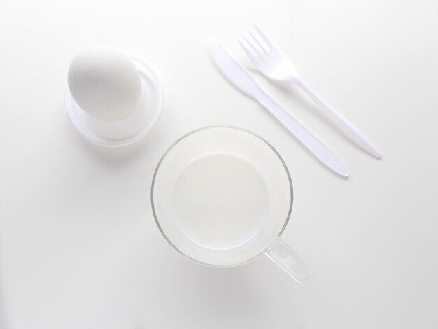 High angle view of white coffee cup white egg and white ustensils on table against white background