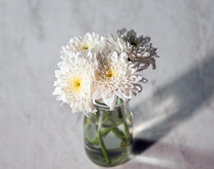 Photo テーブルの上のガラスの花瓶の中の白い花の高角度の景色