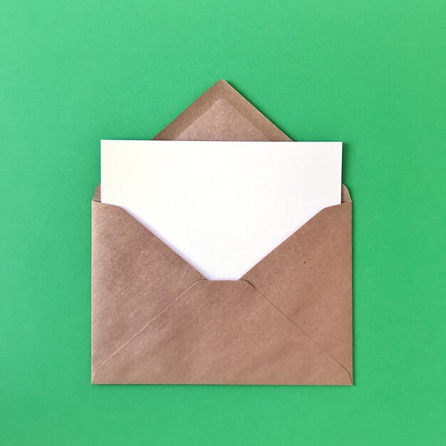 High angle view of white paper in envelope against green background
