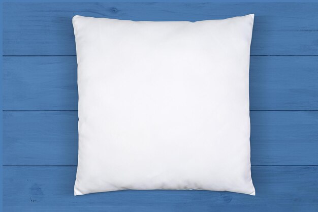 Высокоугольный вид белой подушки на синем деревянном фоне