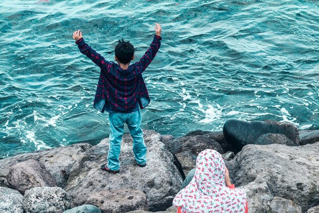 Photo high angle view of woman and boy on rocks by sea