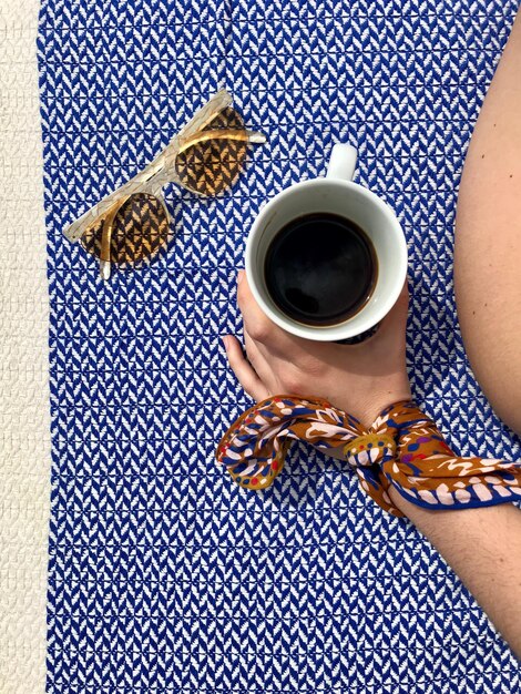 Foto vista ad alto angolo di una donna che tiene una tazza di caffè sul tavolo