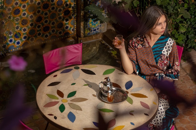 Foto vista ad alto angolo di una donna che tiene una bevanda in bicchiere mentre è seduta vicino alle piante