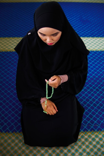 high angle view of woman holding prayer beads while sitting at religious place