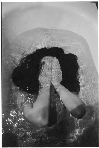 High angle view of woman lying in water at bath tub