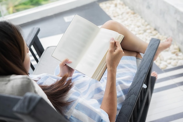 Foto vista ad alta angolazione di una donna che legge un libro seduta su una sedia