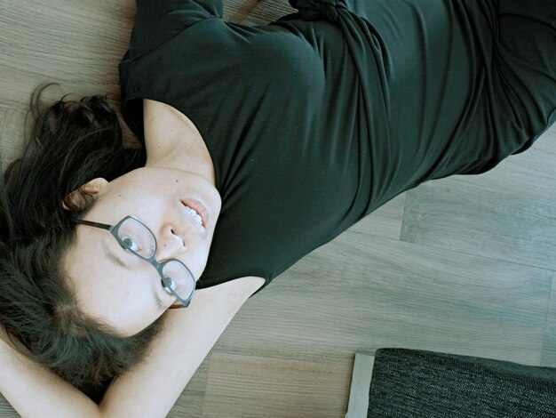 Photo high angle view of woman relaxing on hardwood floor at home