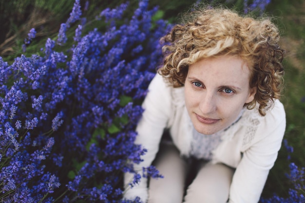 Foto vista ad alto angolo di una donna seduta vicino a fiori di lavanda sul campo