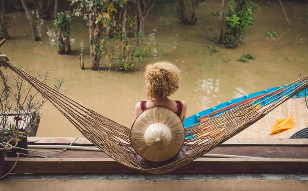 Photo high angle view of woman sitting on hammock by swamp in forest