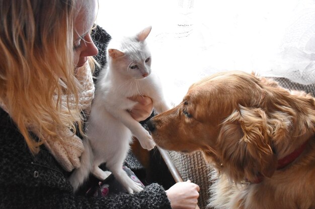 Foto vista ad alto angolo di una donna seduta a casa con un gatto e un cane