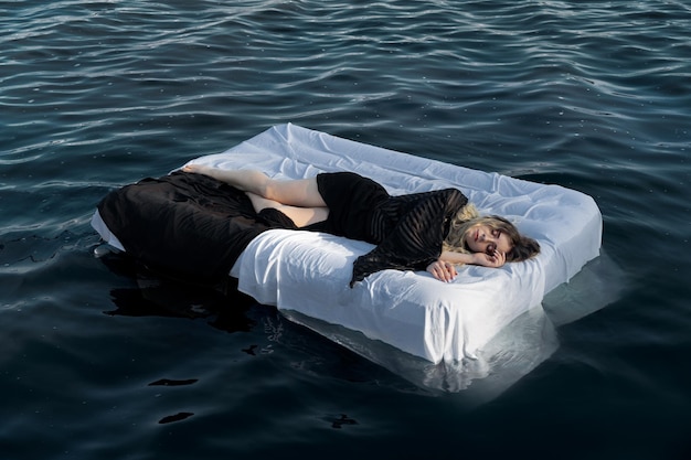 Foto vista ad alta angolazione di una donna che dorme su un materasso in mare