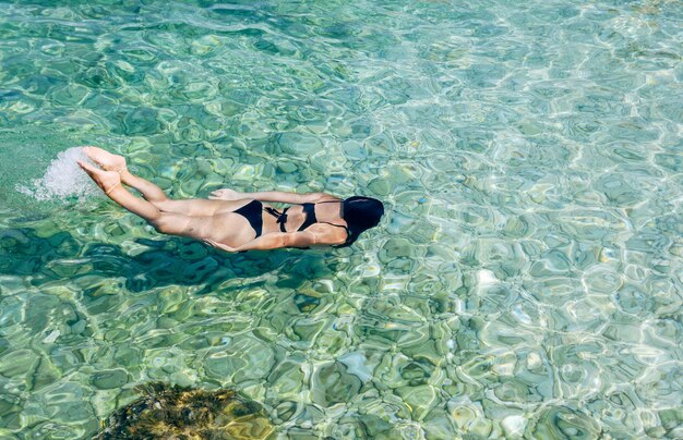 High angle view of woman swimming and diving in turquoise colored sea water