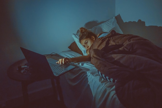 Photo high angle view of woman using laptop while lying on bed at home