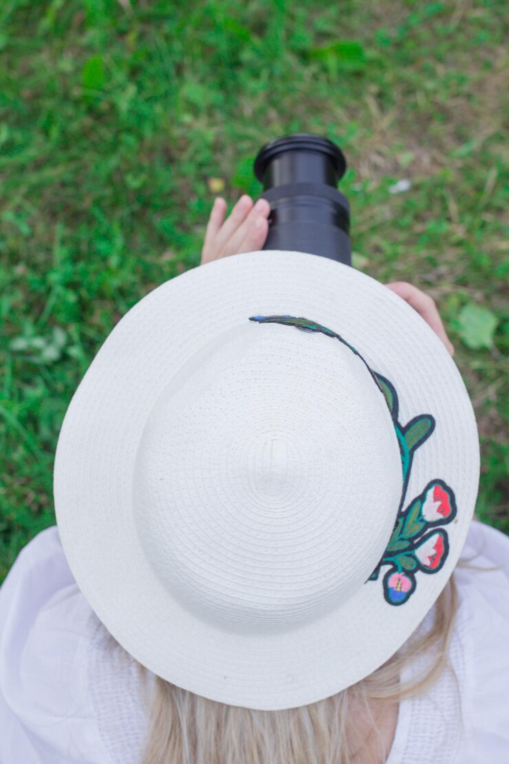 Photo high angle view of woman wearing hat photographing while standing on field