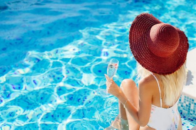 High angle view of woman wearing hat sitting by poolside
