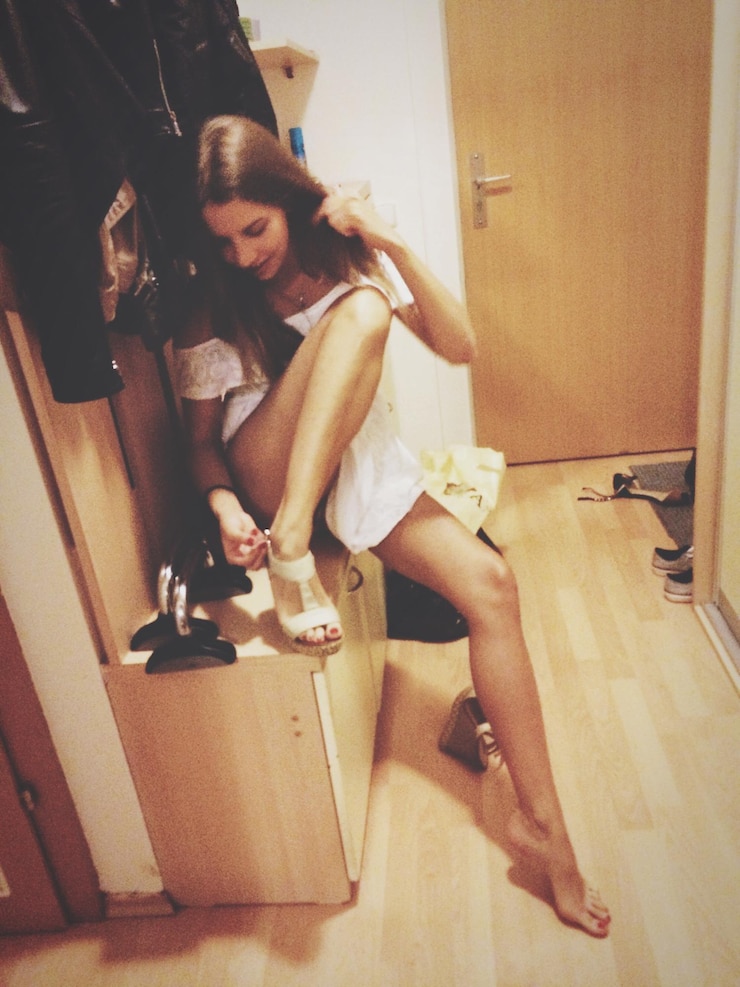 Photo high angle view of woman wearing sandal while sitting on cabinet at home