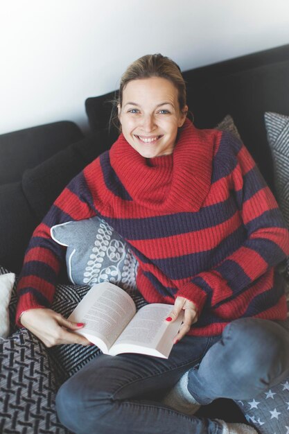 Photo high angle view of woman with book sitting on sofa at home