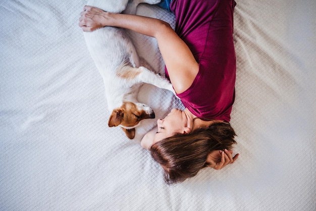 犬がベッドに横たわっている女性のハイアングルビュー