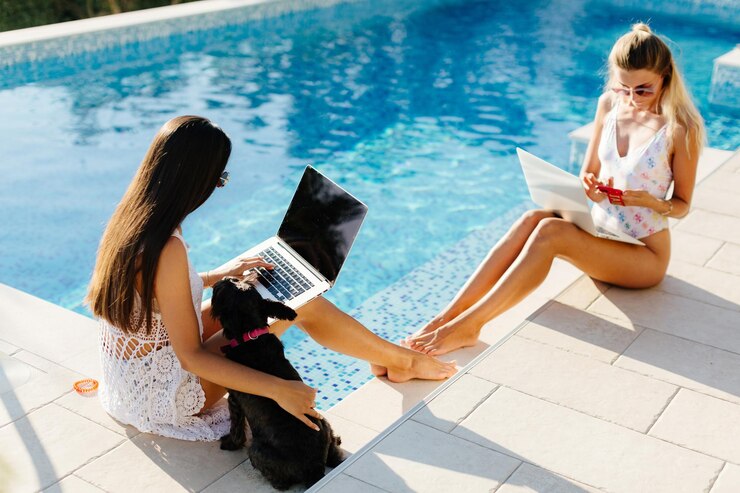Photo high angle view of women using laptop while sitting by swimming pool
