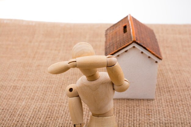 Photo high angle view of wooden figurine and model home on burlap