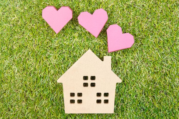 High angle view of wooden house toy with heart shape paper boxes on grassy field