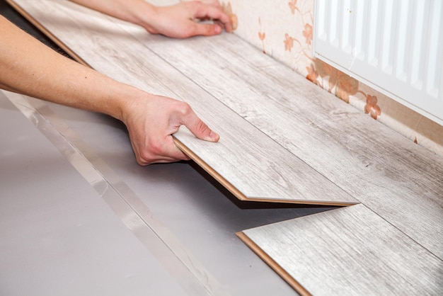 Foto vista ad alto angolo del lavoratore che posiziona il pavimento in legno duro a casa