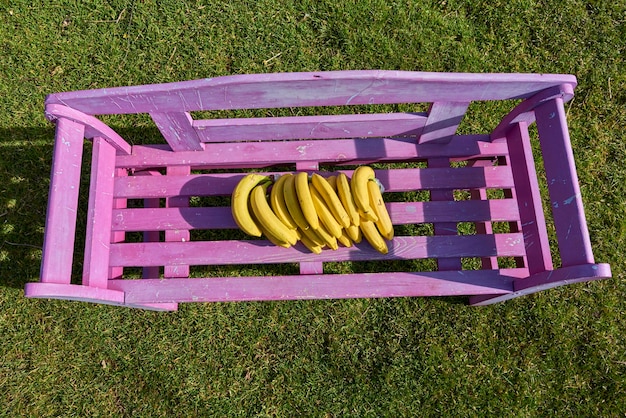 Photo high angle view of yellow bananas on purple bench