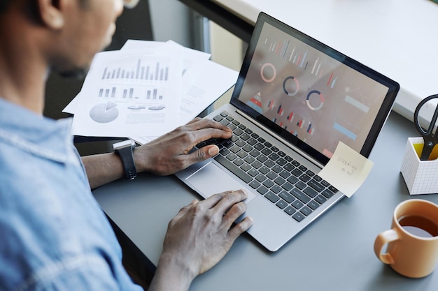 High angle view at young data analyst using computer with charts on screen and typing copy space