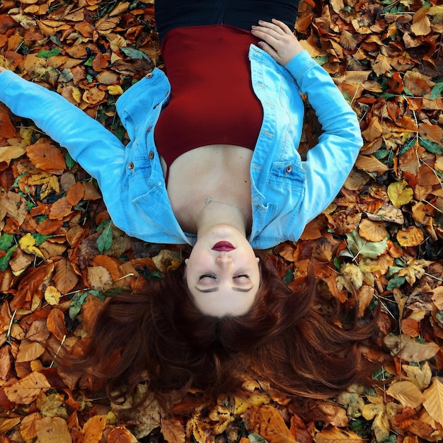 Foto vista ad alto angolo di una giovane donna sdraiata sulle foglie d'autunno