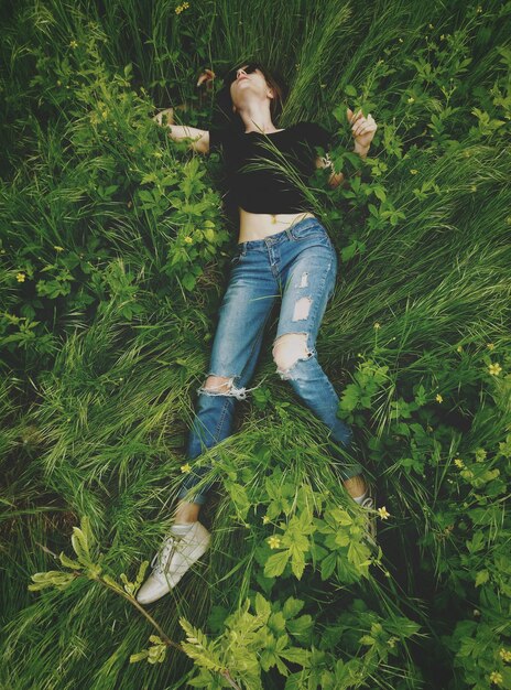 Foto vista ad alto angolo di una giovane donna sdraiata sulle piante nel campo