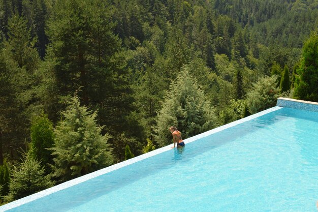 Photo high angle view of young woman standing in swimming pool at forest