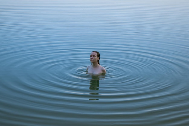 湖で泳いでいる若い女性の高角度の写真