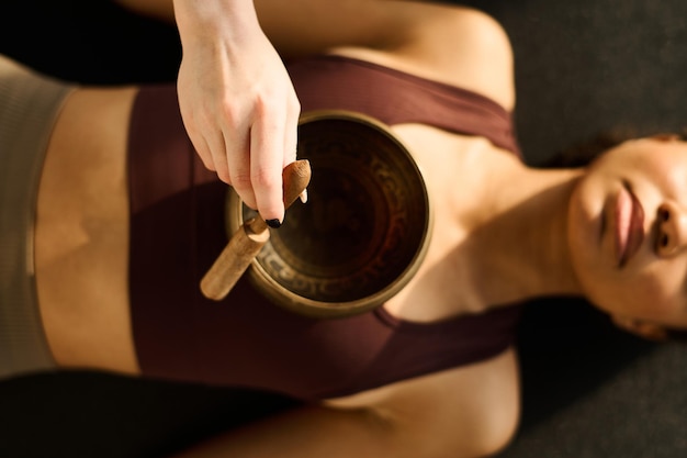 High angle view of young woman using singing bowl in yoga practice together with instructor