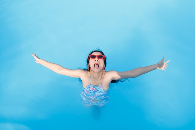 High angle view of young woman with arms outstretched swimming in pool
