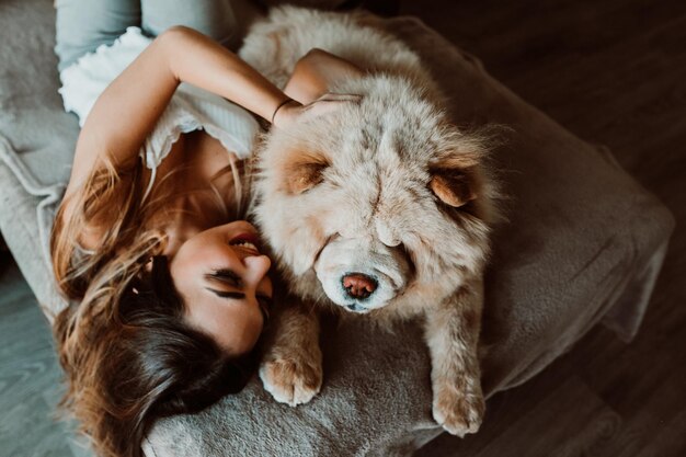 Photo high angle view of young woman with dog lying on bed at home