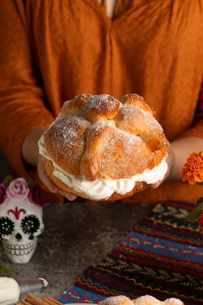 크림과 함께 pan de muerto를 들고 여자의 높은 각도