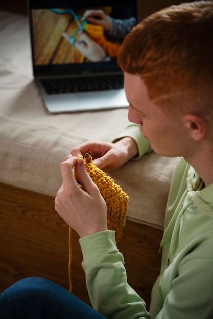 high angle young man knitting at home