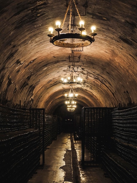 high arched ceiling with chandeliers and rows of champagne bottles in the basement of an old winery