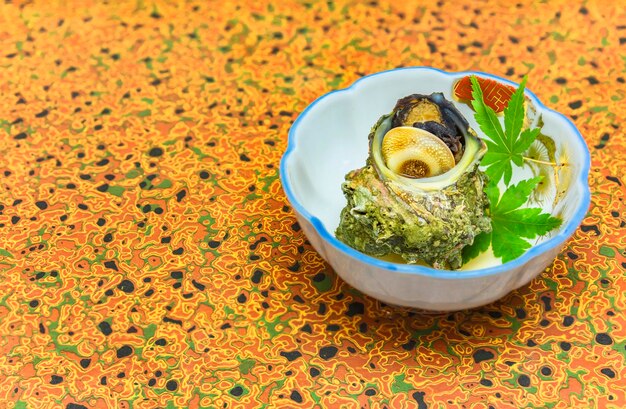 写真 伝統的な日本料理 ツボヤキ 蒸しサザエ 角のついたターバン 海のカタツムリ
