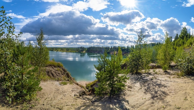 A high cliff with a path on the shore of a lake with snowwhite clouds in the sky