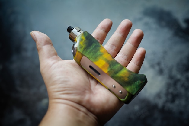 High end yellow green stabilized wood regulated box mods with rebuildable dripping atomizer in hand